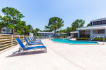 Spacious pool area with lounge chairs at Palms at Sand Lake apartments, surrounded by greenery.