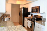 Modern kitchen in an unoccupied one-bedroom apartment for rent in Sunny Isles, featuring stainless steel appliances and granite countertops.