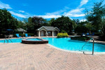 Luxurious pool area at Carrington Park Apartments with sunny blue skies and inviting water.