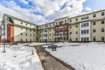 Exterior view of apartments at 59 Broad St, Plattsburgh with snow, featuring benches and modern architecture