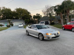 2004 Supercharged GTO in silver parked on a residential street, showcasing its sleek design and muscle car features.