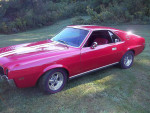 1968 AMC AMX in striking red with white stripes, showcasing its restored interior and powerful 401 CID engine.