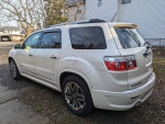 Side view of a 2012 GMC Acadia Denali with premium wheels and tinted windows, parked outdoors.