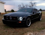 2006 Ford Mustang GT in black with aftermarket modifications parked outdoors
