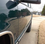 Side view of a 1996 Chevrolet Tahoe LT RWD showcasing its shiny exterior and wheels on a driveway.