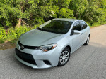 2016 Toyota Corolla parked on a road, excellent condition with new tires and 100,000 miles for sale.