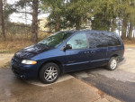 2000 Dodge Grand Caravan parked, showing roof rack and signs of wear, ideal for commuting and family trips.