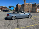 2000 BMW 3 Series 328i convertible in silver, parked in an open lot, showcasing its sleek design.