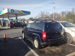 2012 Jeep Patriot 4x4 parked at a gas station, featuring a roof rack and clean exterior.