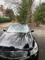 Front view of a 2009 Infiniti G37 sedan in black color, parked outdoors with trees in the background.