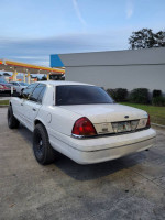 2001 Ford Crown Victoria with a body lift and off-road tires parked at a gas station