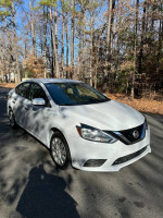 2017 Nissan Sentra in great condition, white color, parked on a road surrounded by trees, ready for sale.