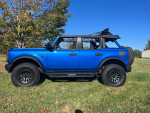 2022 Ford Bronco Big Bend 4WD in blue with a 2-inch lift and new tires parked in a grassy area.