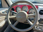 Interior view of a 2006 Chrysler PT Cruiser showing dashboard and steering wheel in red and beige.
