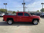 Side view of a 2014 GMC Sierra 1500 SLE in fire red, showcasing its sleek design and alloy wheels.