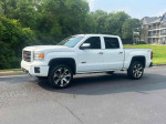 2014 GMC Sierra 1500 Regular Cab 4WD in white, parked on pavement with lush greenery in background, showcasing sleek design.