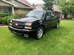 Black 2003 Chevrolet Silverado 1500 SS parked on green grass, showcasing its sporty design and powerful 6.0L V8 engine.