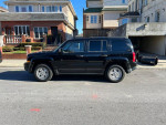 2015 Jeep Patriot Sport in black, parked on the street, featuring clean lines and alloy wheels.