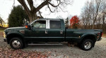2010 Ford F350 Dually Super Duty Diesel truck parked on gravel with forest backdrop, showcasing its custom features.