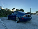 2003 Lexus IS 300 RWD in blue, lowered on coilovers, parked with nature in the background.