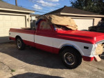 1969 GMC 1500 truck with red and white paint, parked outside with new parts, in good condition for its age.