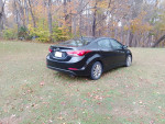 2015 Hyundai Elantra SE sedan in excellent condition, parked on grass with autumn foliage in the background.