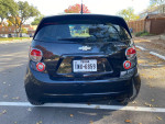 Rear view of a 2014 Chevrolet Sonic LT hatchback in a parking lot, showcasing its black color and aluminum wheels.