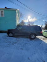 2010 Ford Expedition parked outside on snow, featuring 3rd row seating and Cooper ATV tires.