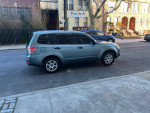 2009 Subaru Forester 2.5X parked on the street, showcasing its clean exterior and all-wheel drive capability.