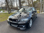 2011 BMW 335i xDrive in black, parked in a scenic outdoor setting with trees.