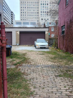 1994 Honda Accord coupe parked in a gravel alley with garages in the background, needing some restoration.
