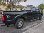Black 2021 Ford F250 Lariat Super Duty 4x4 truck with luxury features and long bed parked on the street.