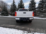 Rear view of a clean 2019 Toyota Tundra parked on a snowy road with trees in the background.