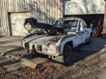 2003 Chevy 3500HD 4x4 wrecker tow truck equipped with Duramax engine and boss plow mount, parked in a lot.