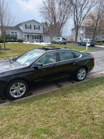 2015 Chevrolet Impala 2LT in black, showcasing its sleek design and well-maintained exterior near a residential area.