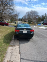 Black 2015 Chevrolet Impala parked on a residential street, showcasing its sleek design and well-maintained condition.