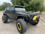 2016 Jeep Rubicon Hard Rock with yellow accents parked outdoors, showcasing its rugged tires and off-road features.