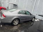 2007 Ford Fusion SEL FWD in gray, parked with visible dents and rust, showcasing aftermarket radio and wheels.