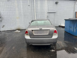 Rear view of a 2007 Ford Fusion SEL in decent condition with visible dents and rust, parked outside.