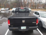 2015 Ram 1500 black truck with backrack and cover parked in a lot, showcasing excellent condition for its mileage