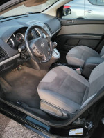 Interior view of a 2011 Nissan Sentra with gray fabric seats and dashboard controls