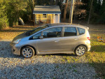 2010 Honda Fit Sport FWD in silver parked on gravel, showcasing its hatchback design and clean exterior.