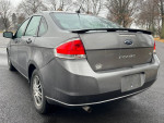 2011 Ford Focus SE sedan in gray, showcasing clean exterior and wheels, parked on wet pavement.