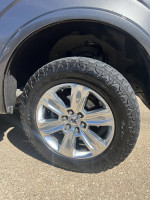 Close-up of the wheel and tire of a 2018 Ford F-150 Platinum with new tires and chrome rims.