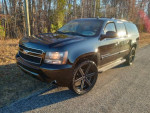 2009 Chevrolet Suburban LTZ in black with 24-inch wheels, parked in nature.