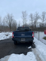 Rear view of a blue 2019 Ford F-250 Super Duty truck parked on a snowy road.