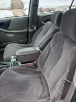 Interior view of a Chevrolet car showing clean grey fabric seats with armrest and cup holder
