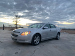 2011 Chevrolet Malibu LT sedan in silver color, parked outdoors during sunset, highlighting its clean design.