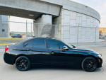 Side view of a black 2016 BMW 320i xDrive with sleek design and alloy wheels, parked in an urban setting.