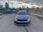 Front view of a 2015 Volkswagen Jetta SE in good condition, parked on a road with cloudy sky.